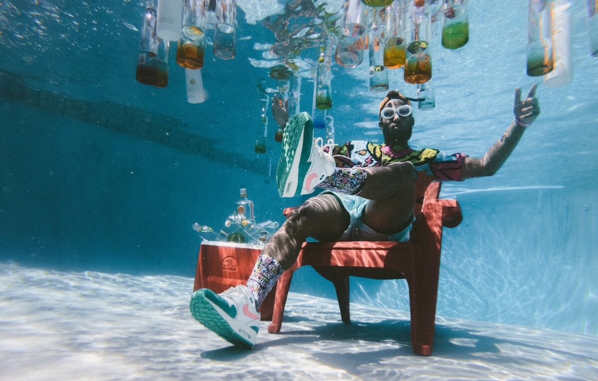 Uomo seduto in piscina con bottiglie di alcolici